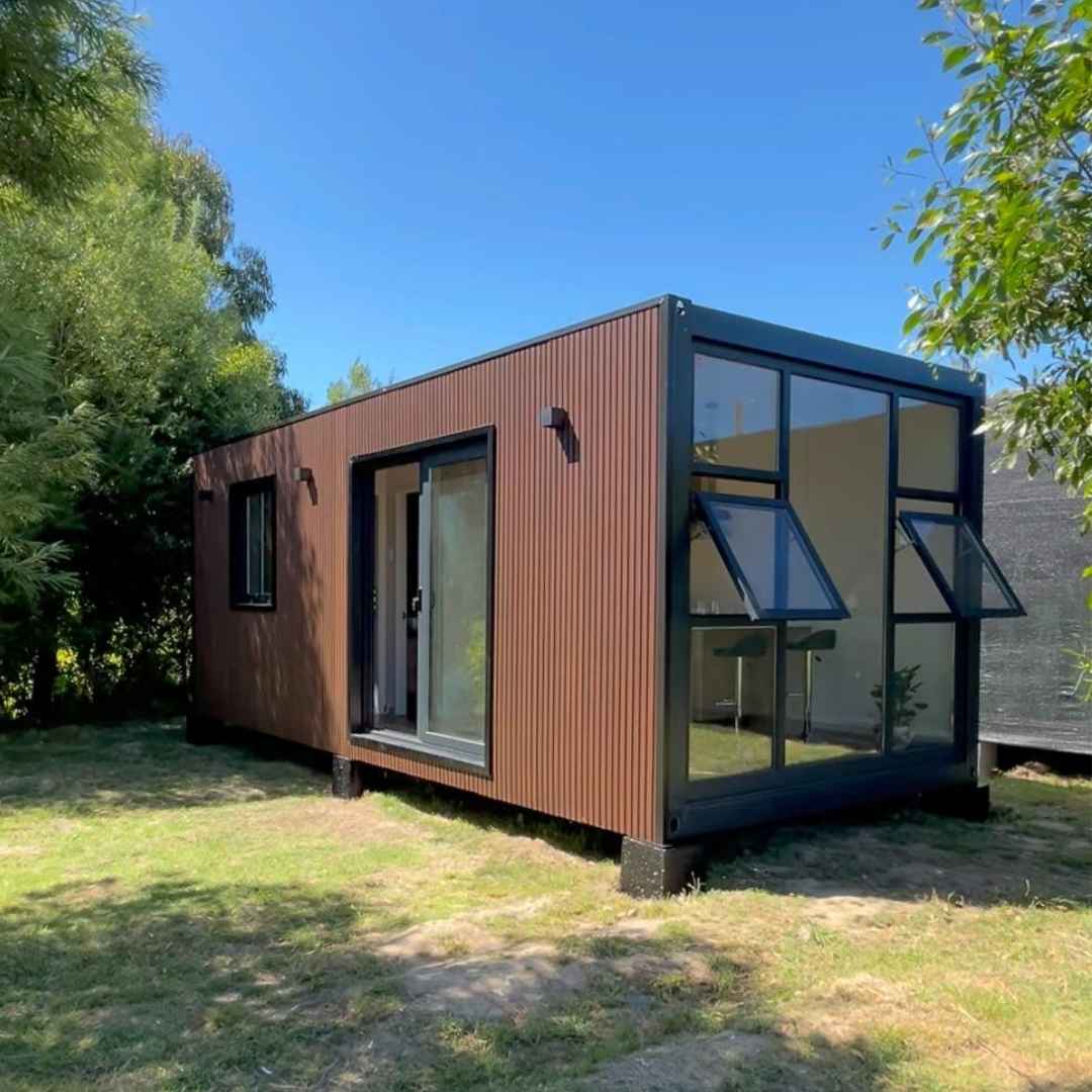 Tiny house modular de 21 m² (3 × 7 m) con gran ventanal lateral y ventanal de acceso frontal, revestida en madera roble oscuro.